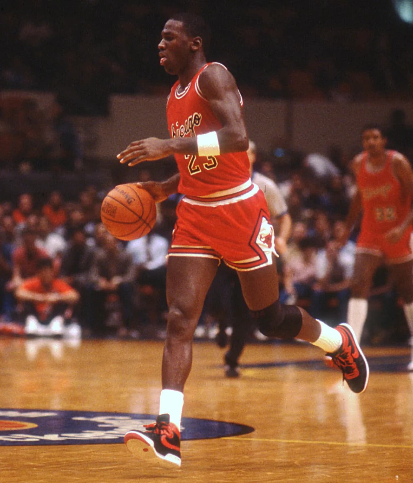Michael Jordan dribbling in a red Chicago Bulls uniform at Madison Square Garden.